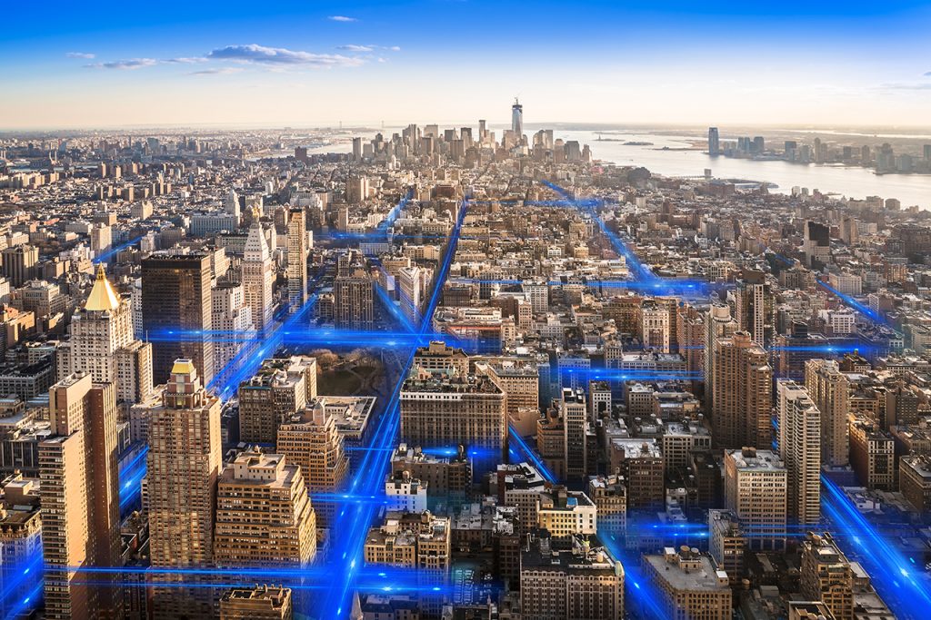 Aerial city skyline with blue digital network lines connecting buildings representing smart city technology and urban connectivity